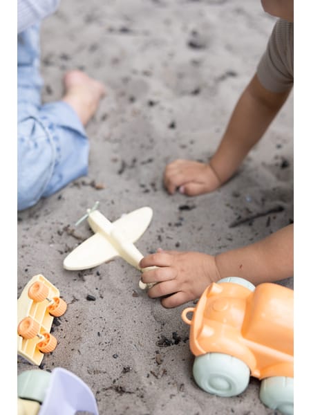 Små huse og fly i pastelfarver orange, gul og blå arrangeret i et spredt mønster.